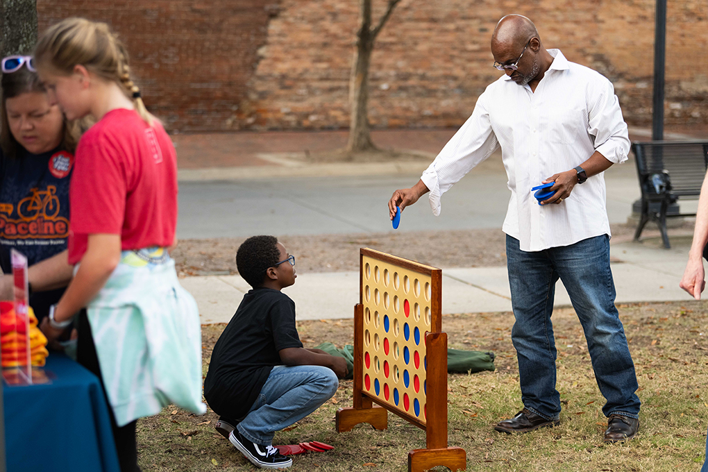 A man and a young boy play a game of Connect Four at a fundraising event.