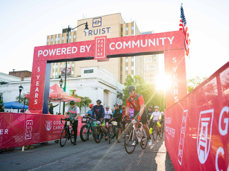 A group of bikers start a race at the starting line.
