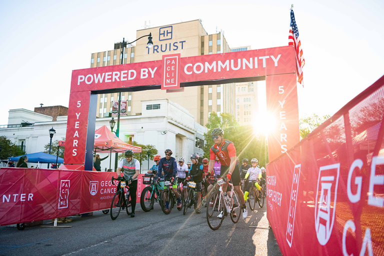 A group of bikers start a race at the starting line.