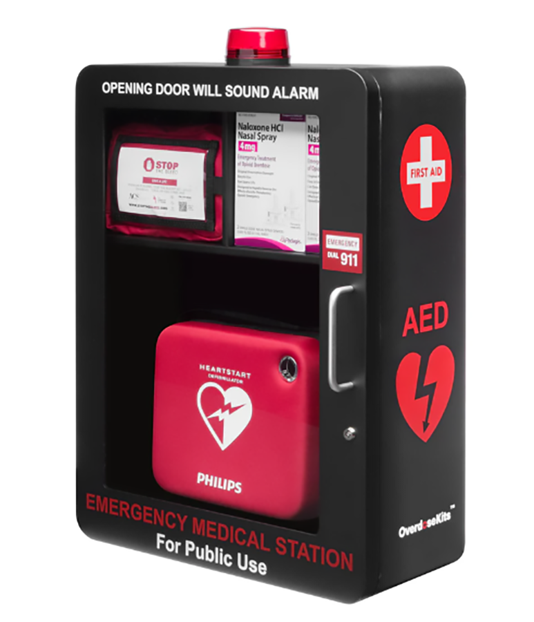 A safety box that includes a Stop the Bleed kit, Narcan opioid reversal spray and an AED kit. The box has a handle and an emergency light on top.