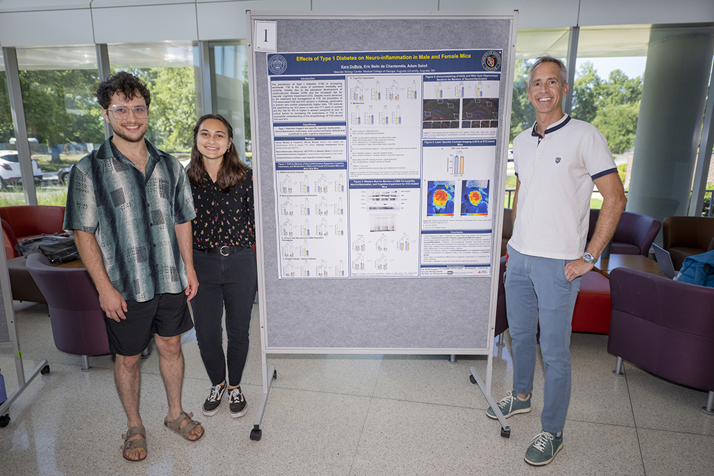 Woman standing with two men next to poster board project