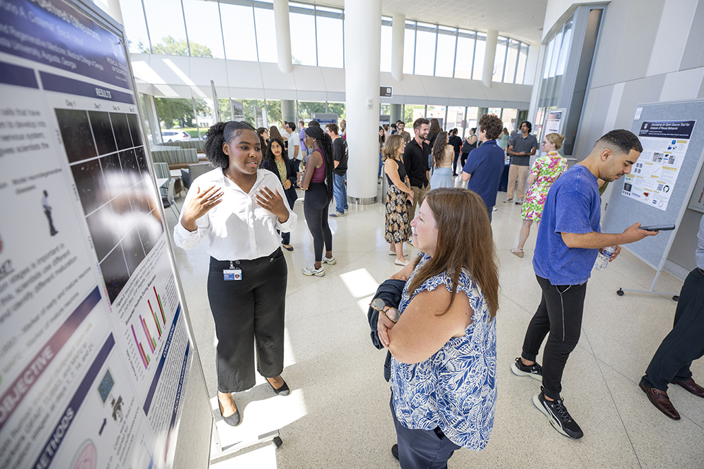 Female student talking to a woman about her poster board project