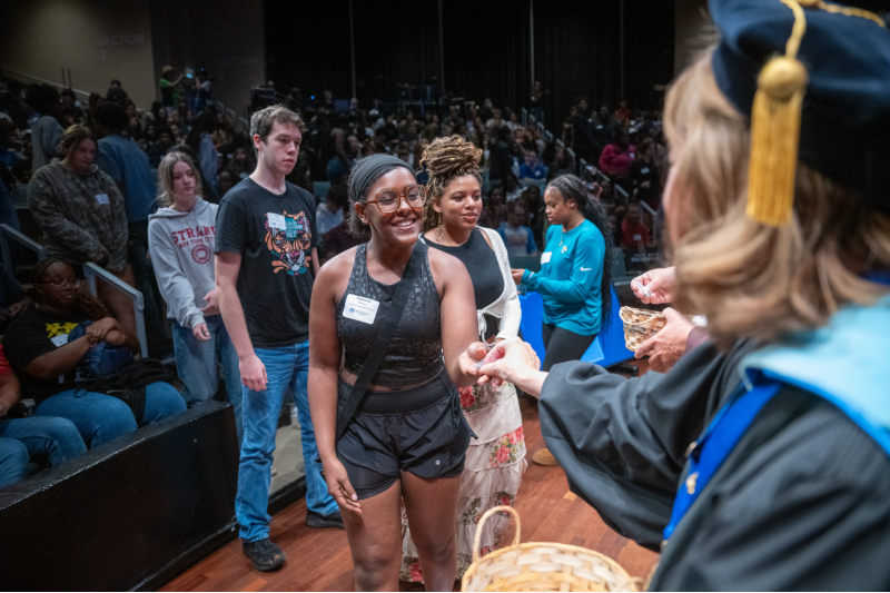 female student smiles at a woman handing her something.