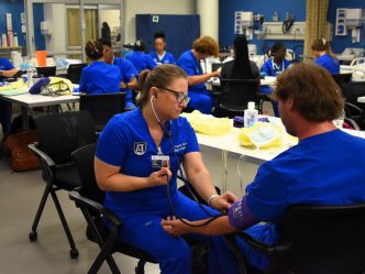 2 BSN students practice taking vitals on each other in a classroom