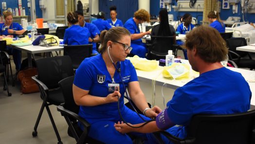 2 BSN students practice taking vitals on each other in a classroom