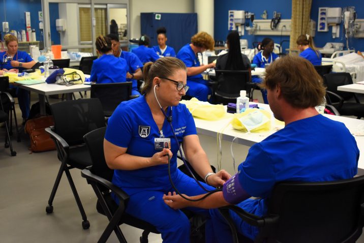 2 BSN students practice taking vitals on each other in a classroom
