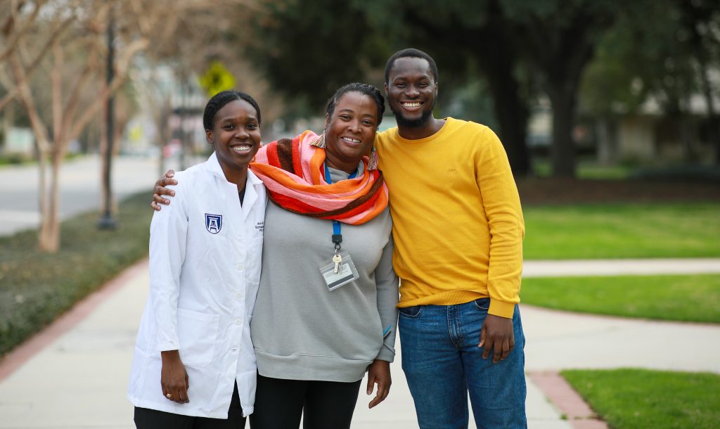 two students stand with mentor