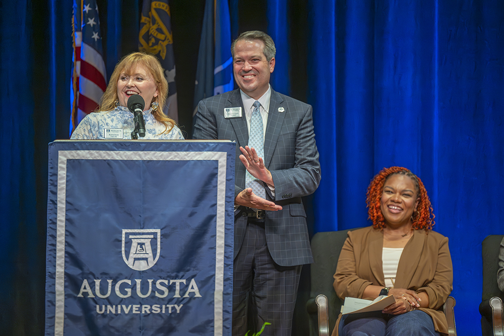 woman and man stand up at a podium