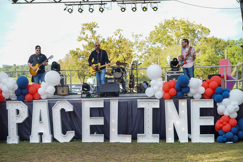 A band performs on a stage that has the word "Paceline" written across the bottom of it.
