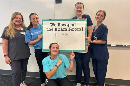 five females standing and kneeling around a sign that says "we escaped the escape room"
