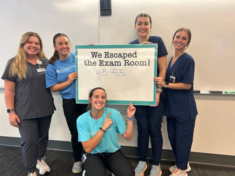 five females standing and kneeling around a sign that says "we escaped the escape room"