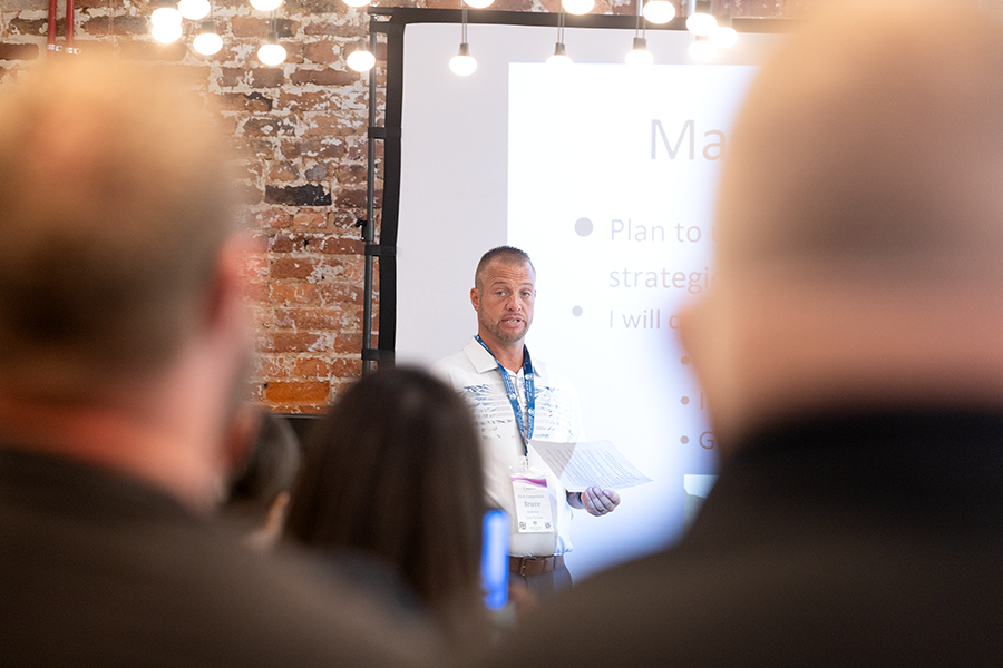 A man gives a presentation to a large group of people gathered in a conference room.