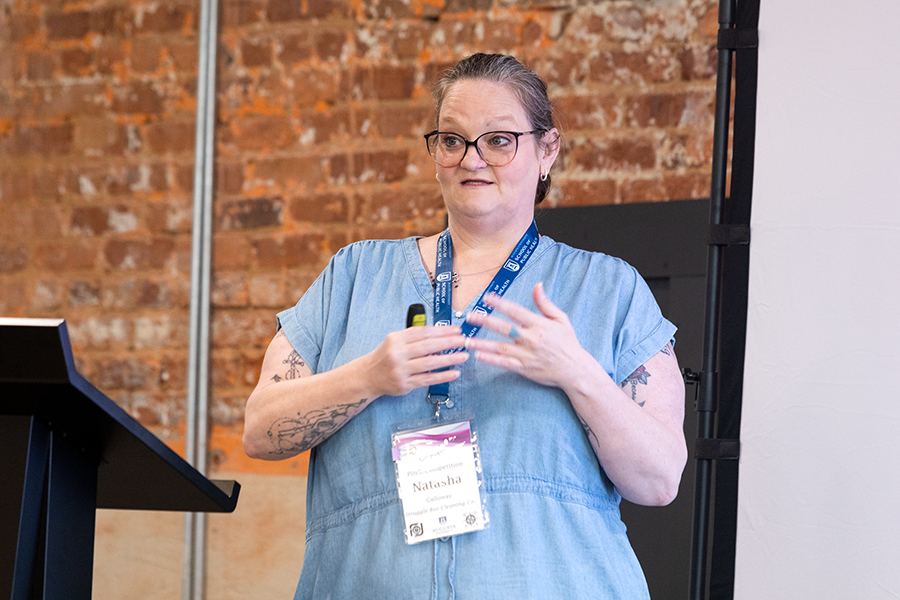 A woman gives a presentation to a large group of people gathered in a conference room.