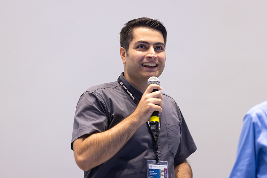 A man stands at a podium with a microphone while speaking to a large group of people gathered in an auditorium.