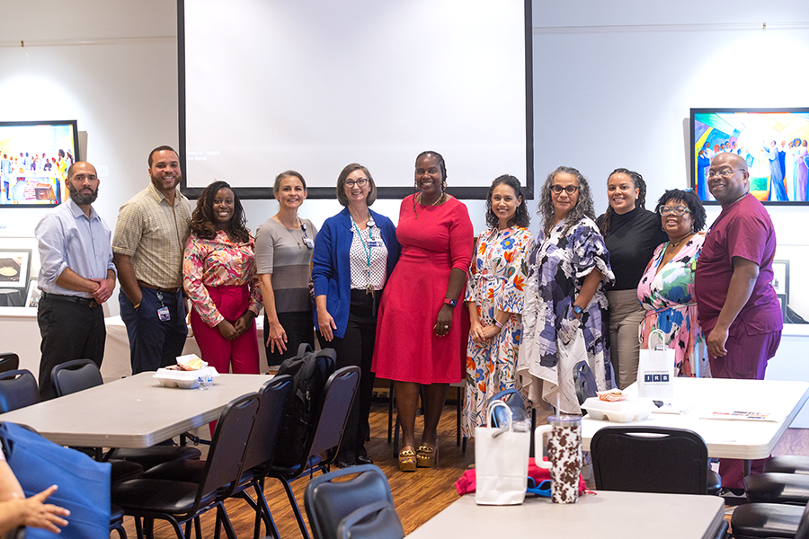 A group of eight women and three men stand together to celebrate a successful event.