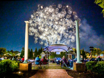 Fireworks over a large crowd of people gathered in an amphitheater.