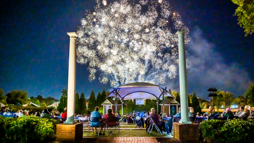 Fireworks over a large crowd of people gathered in an amphitheater.