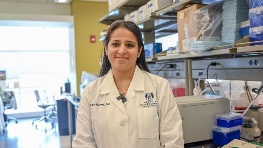 Woman wearing a scientific lab coat standing in a research lab.