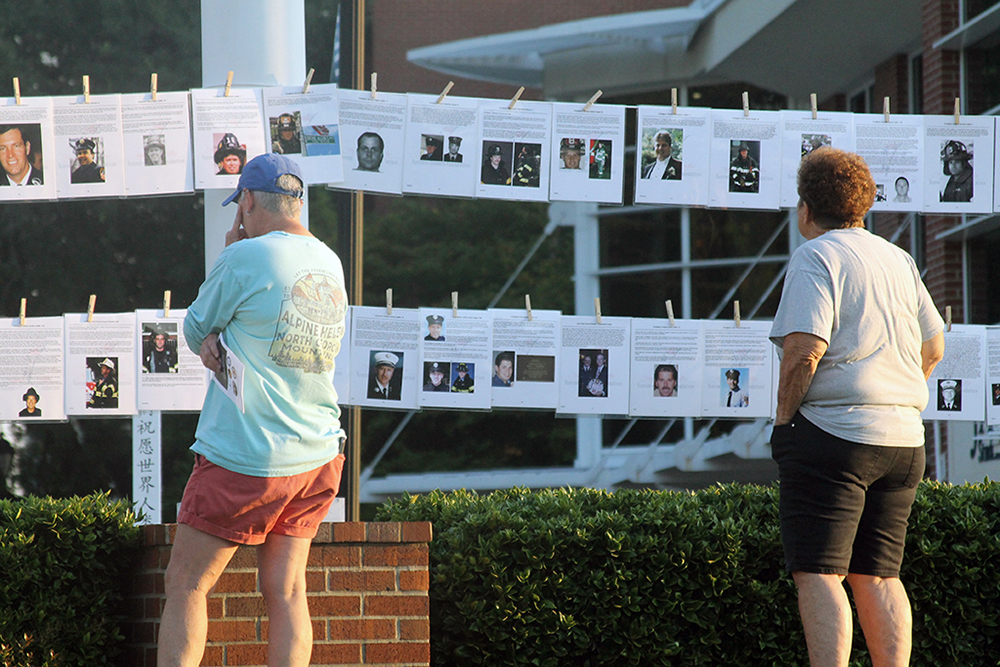 Man and woman looking at photos on a line of those who lost their lives on 9/11