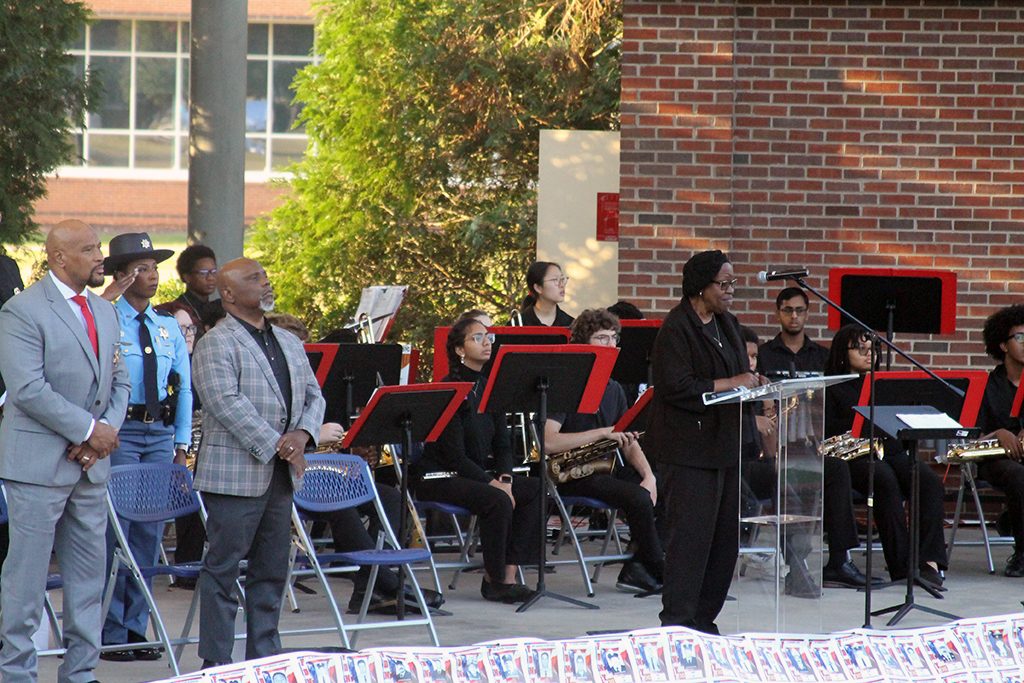 Men and women on a stage singing and listening