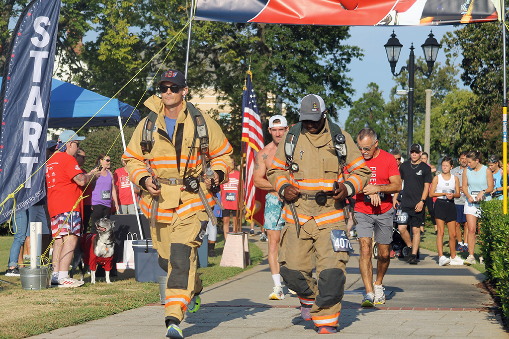 Runners in uniform cross the start/finish line