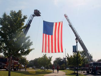 Giant United States flag hanging from two firetrucks