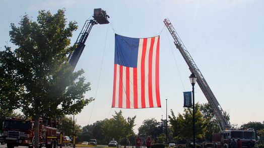 Giant United States flag hanging from two firetrucks
