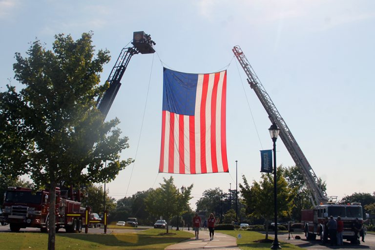 Giant United States flag hanging from two firetrucks
