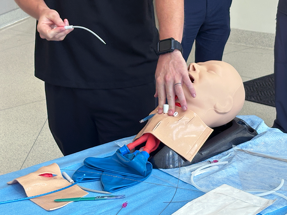 A pulmonologist performs a tracheostomy on a medical mannequin.