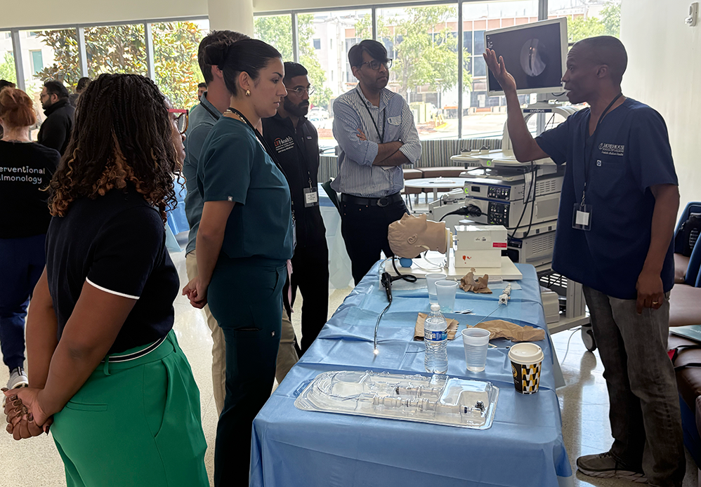 Pulmonology fellows gather around a table to learn a medical technique.