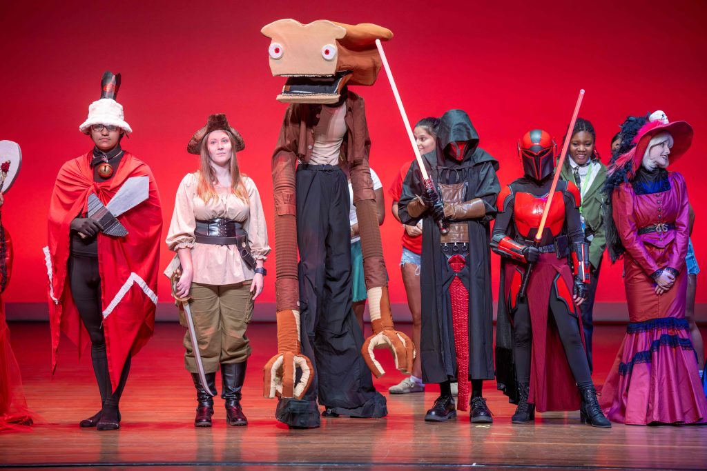 College-aged students in line on a stage dressed in costumes for a cosplay contest.