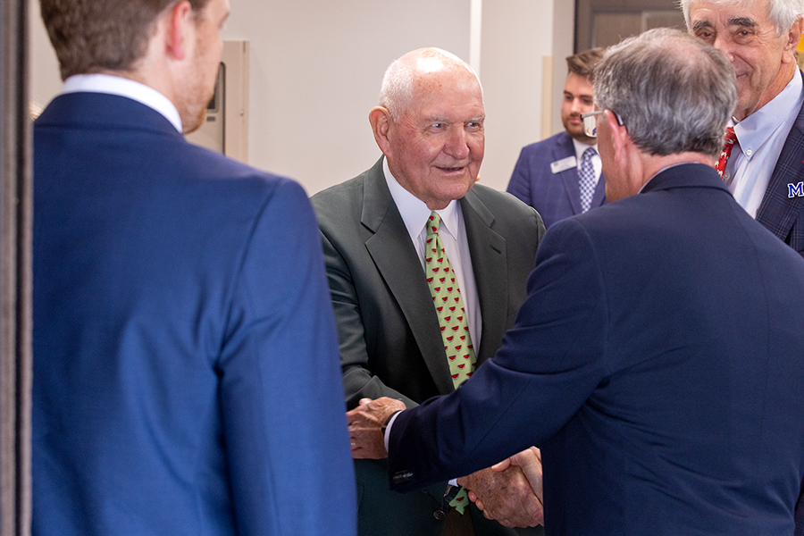 An older man shakes hands with another man.