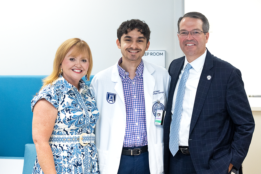 A man and a woman stand with a male medical student.