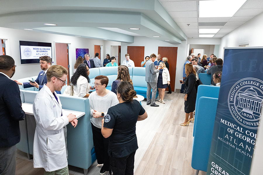People stand around in a large space mingling during a social event.