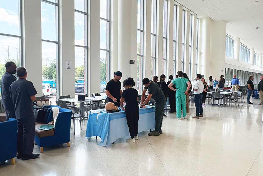 Medical fellows gather at different stations in a medical school lobby to learn pulmonary procedures.