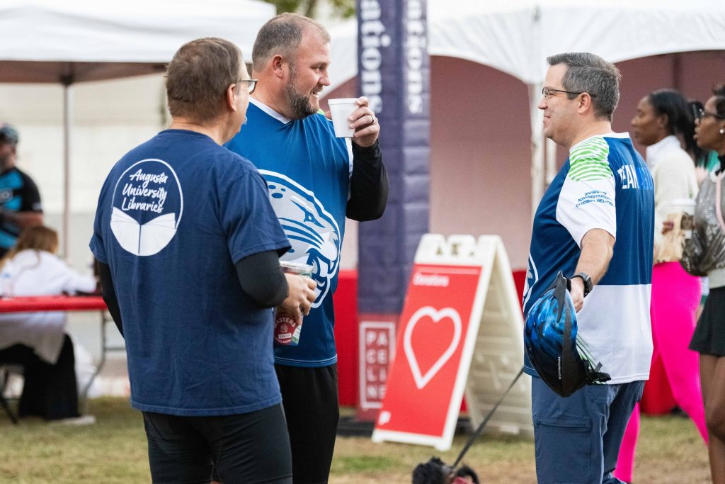 Three men stand and talk before the PaceDay 2023 event.