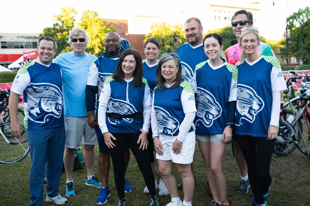 A photo of men and women posing for the picture. The people in the photo are part of Team Jaguar riding in PaceDay 2023.