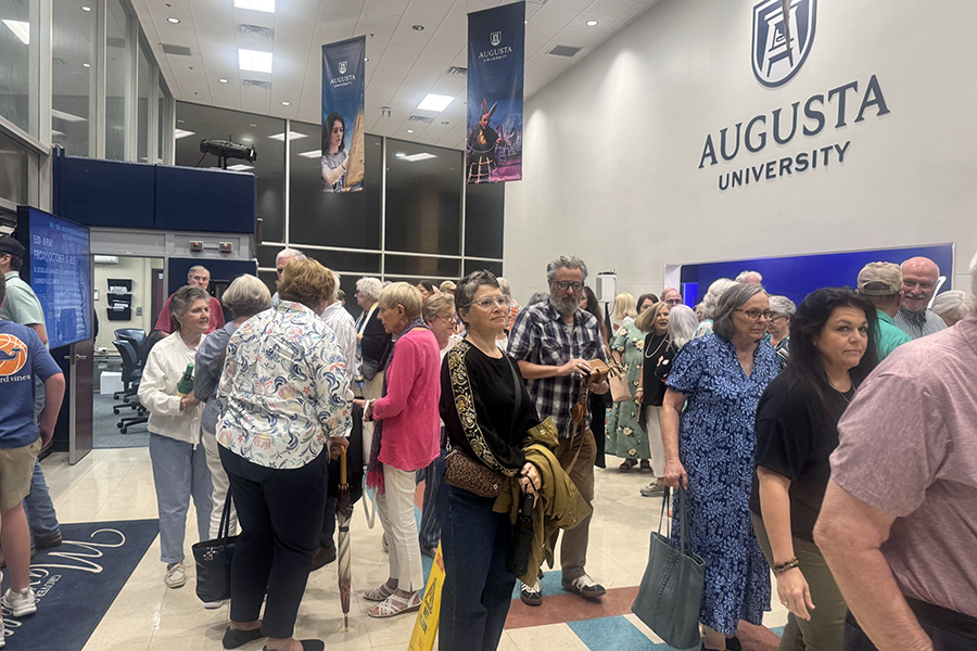 People gathered in the entryway to a local theatre on a college campus.