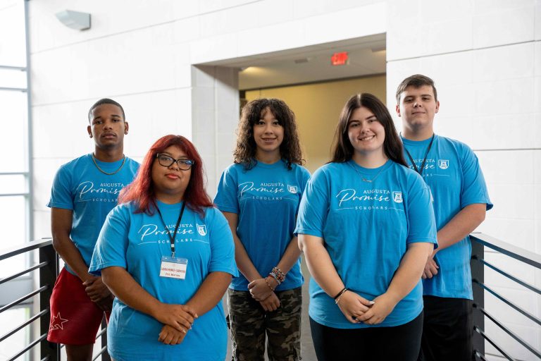 A group of men and women pose for a photo inside a building.