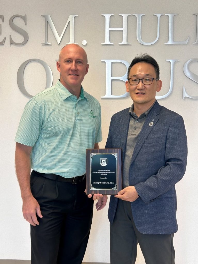 Two men standing next to each other, one holds a plaque.