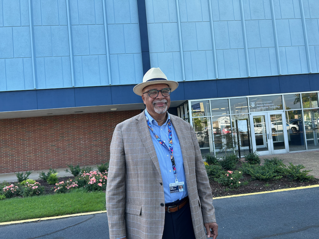 A man stands in front of a building that was freshly renovated.