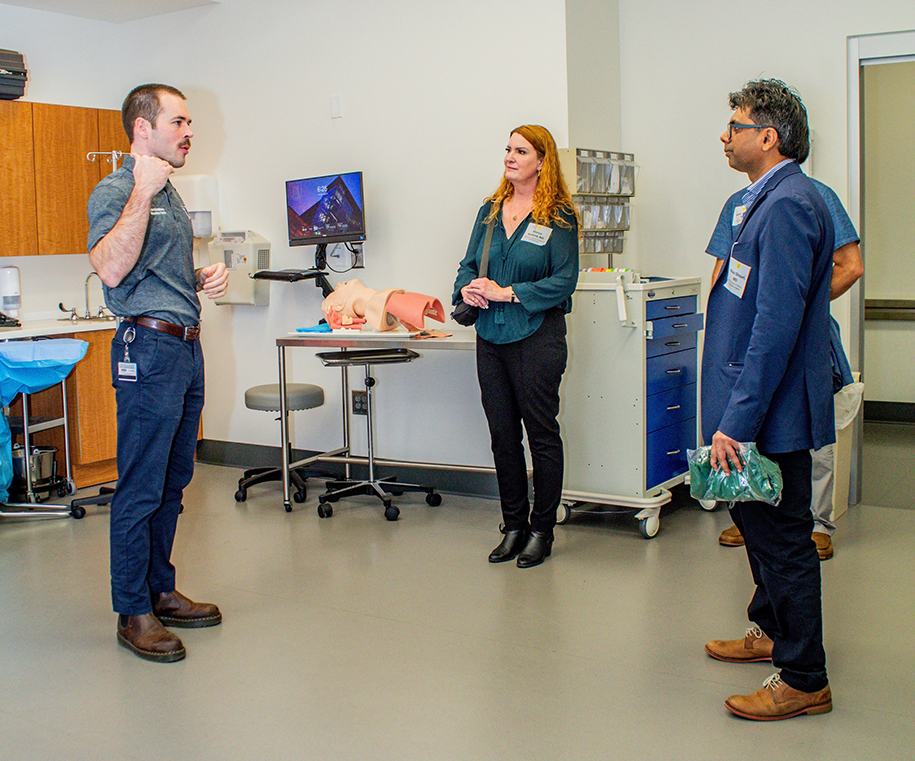 Two men and a woman have a conversation in a medical lab room.