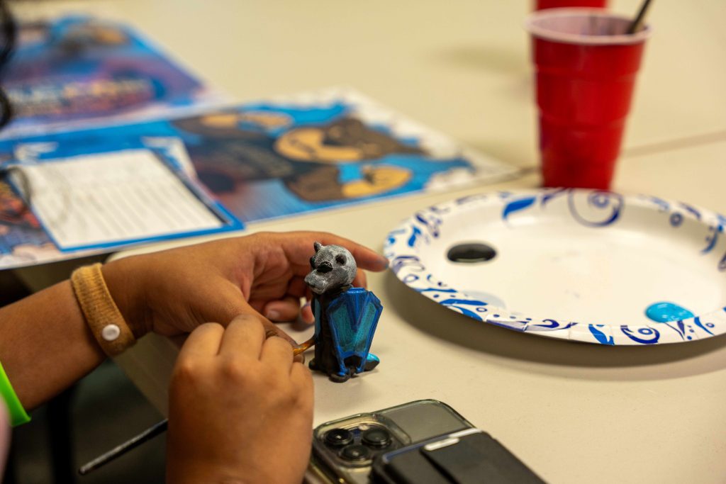 A college student paints a mini figurine.