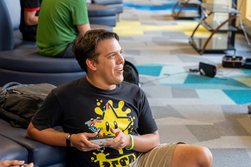 A male college student plays a video game with a controller.