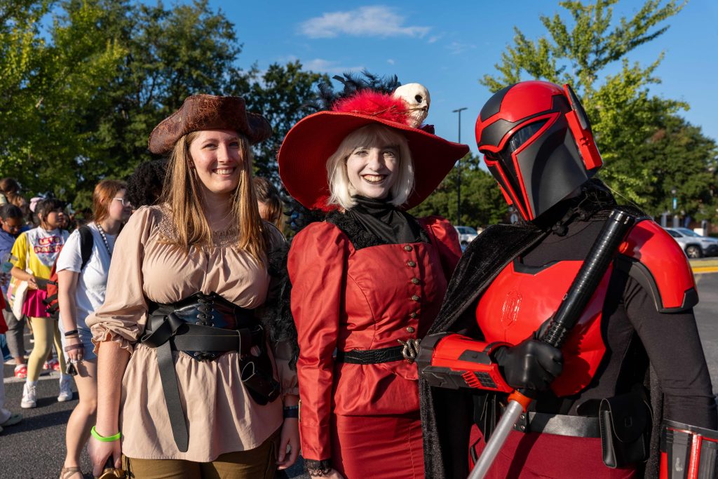 Three female college students wear costumes during an event.