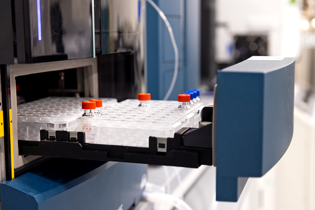 A close up shot of tester bottles arranged in the tray of a machine in a scientific lab.