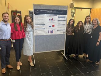 Men and women standing by a poster board