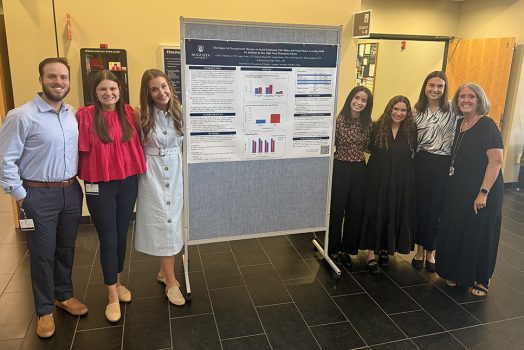 Men and women standing by a poster board