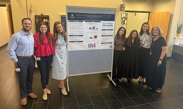 Men and women standing by a poster board