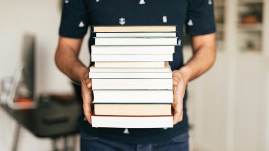 A person holding a stack of books